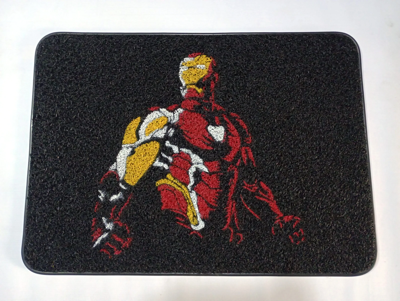 Tapete personalizado negro con ilustración de Iron Man en tonos rojos, amarillos y blancos, con textura atrapamugre y bordes redondeados, fotografiado sobre fondo blanco.